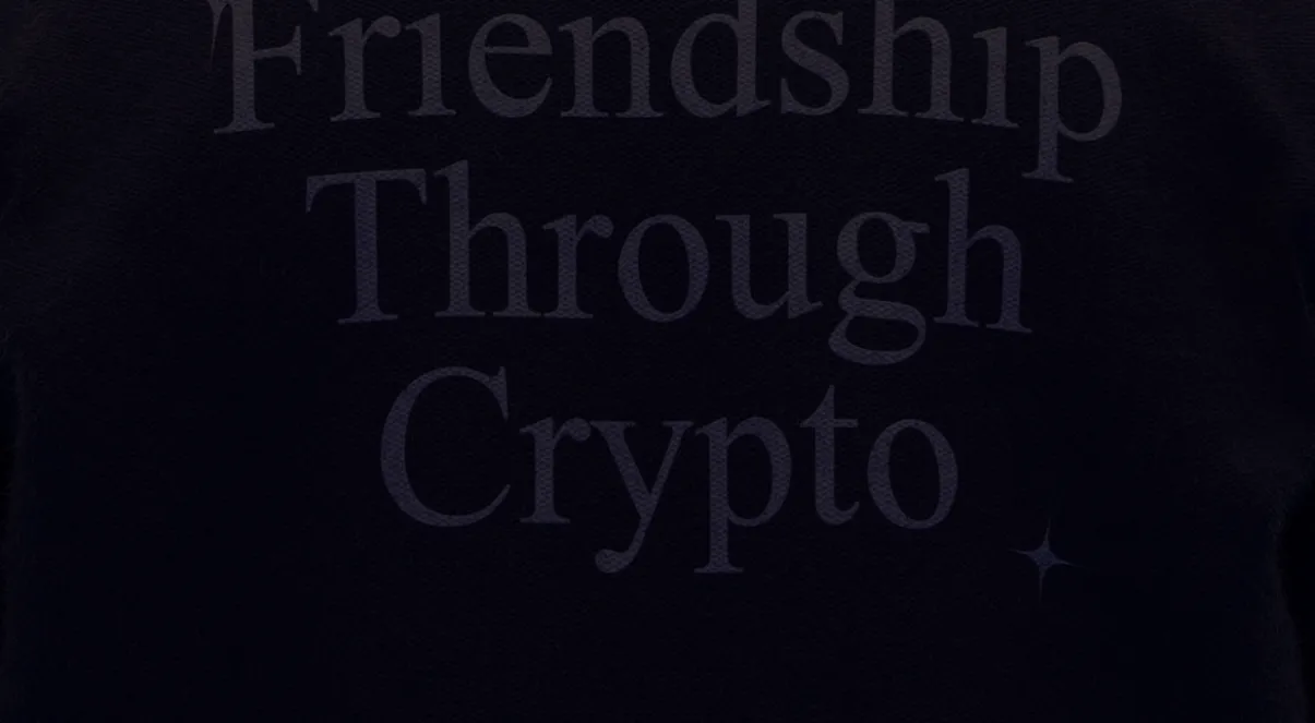 Close-up van de donkere trui met de geborduurde woorden 'Friendship Through Crypto'